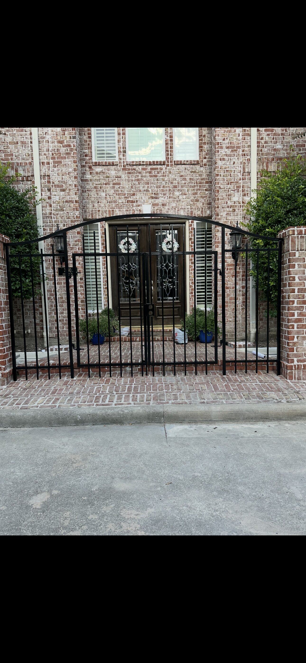 Decorative iron walk gate at brick home